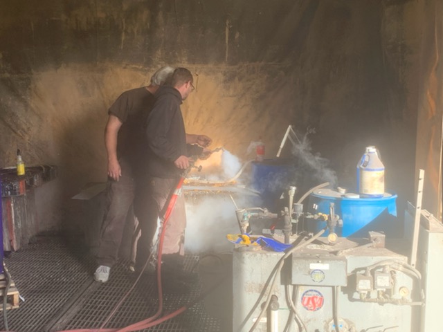 two men sandblasting in a shop